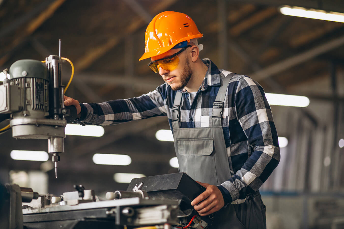 Zerspanungsmechaniker mit orangem Helm bei der Arbeit